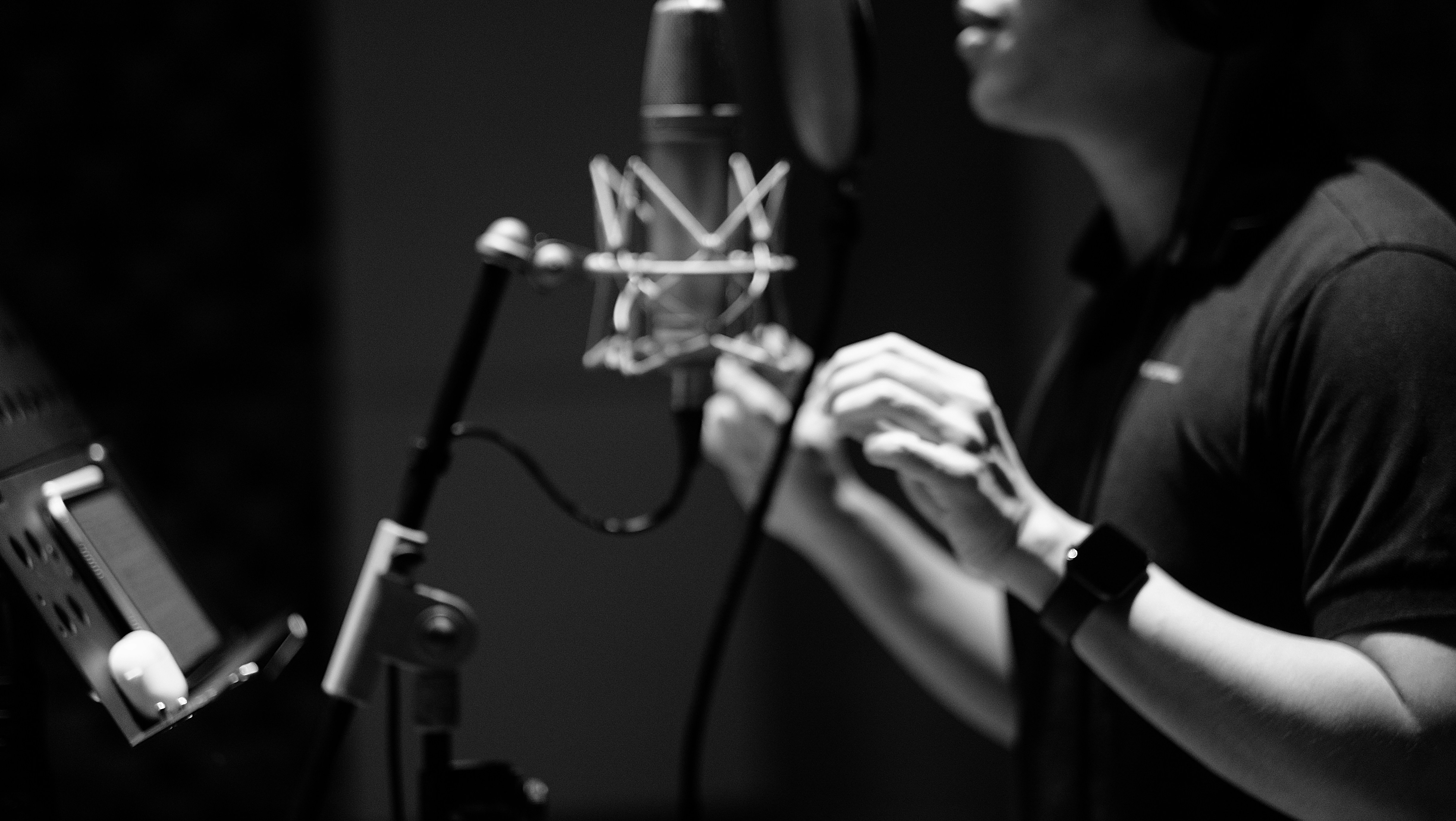 A man singing into a mic in a music studio. Photo by David Kristianto on Unsplash