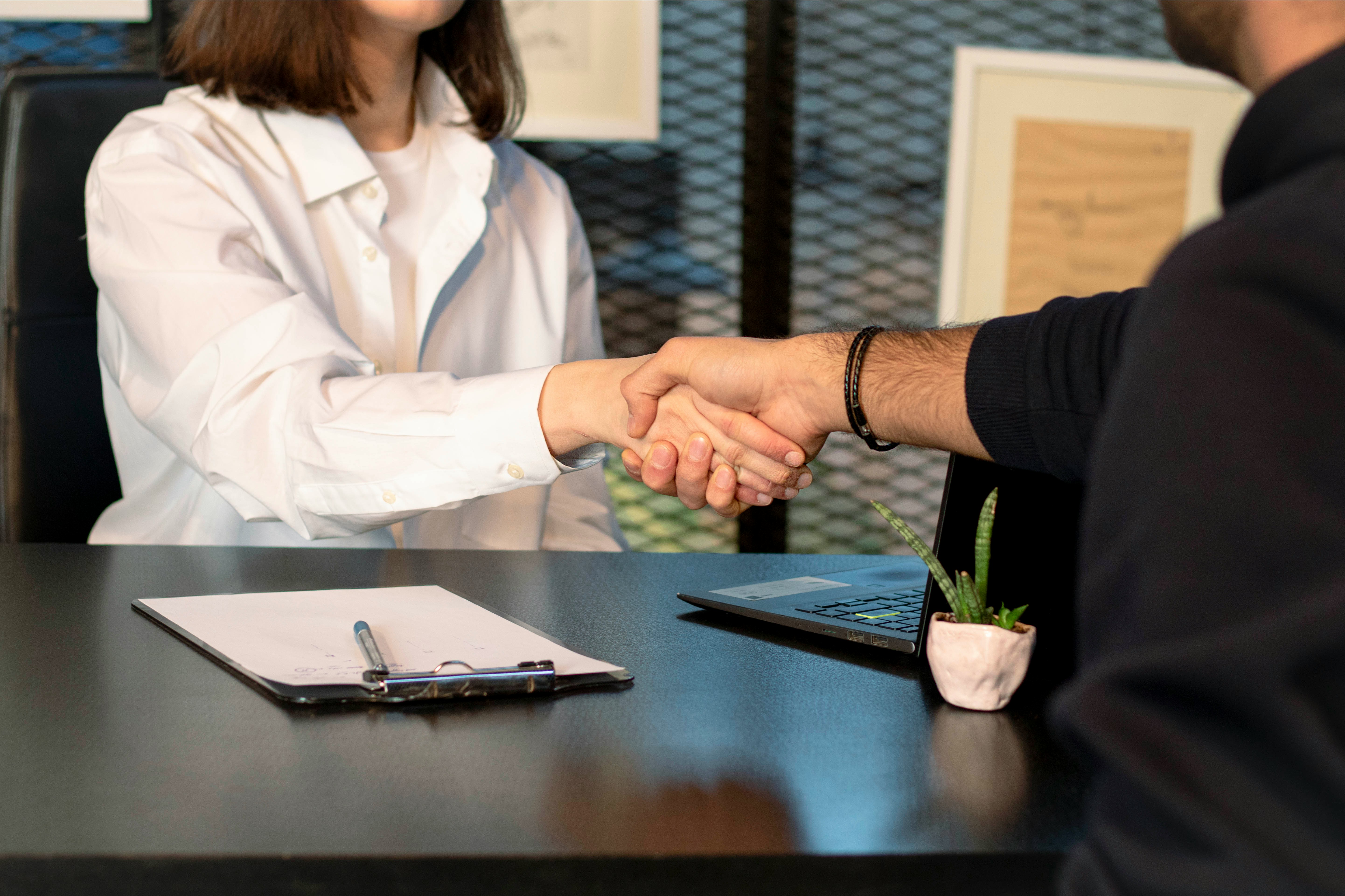 Two people in a conference coming to an agreement and shaking hands. Photo by Mina Rad on Unsplash