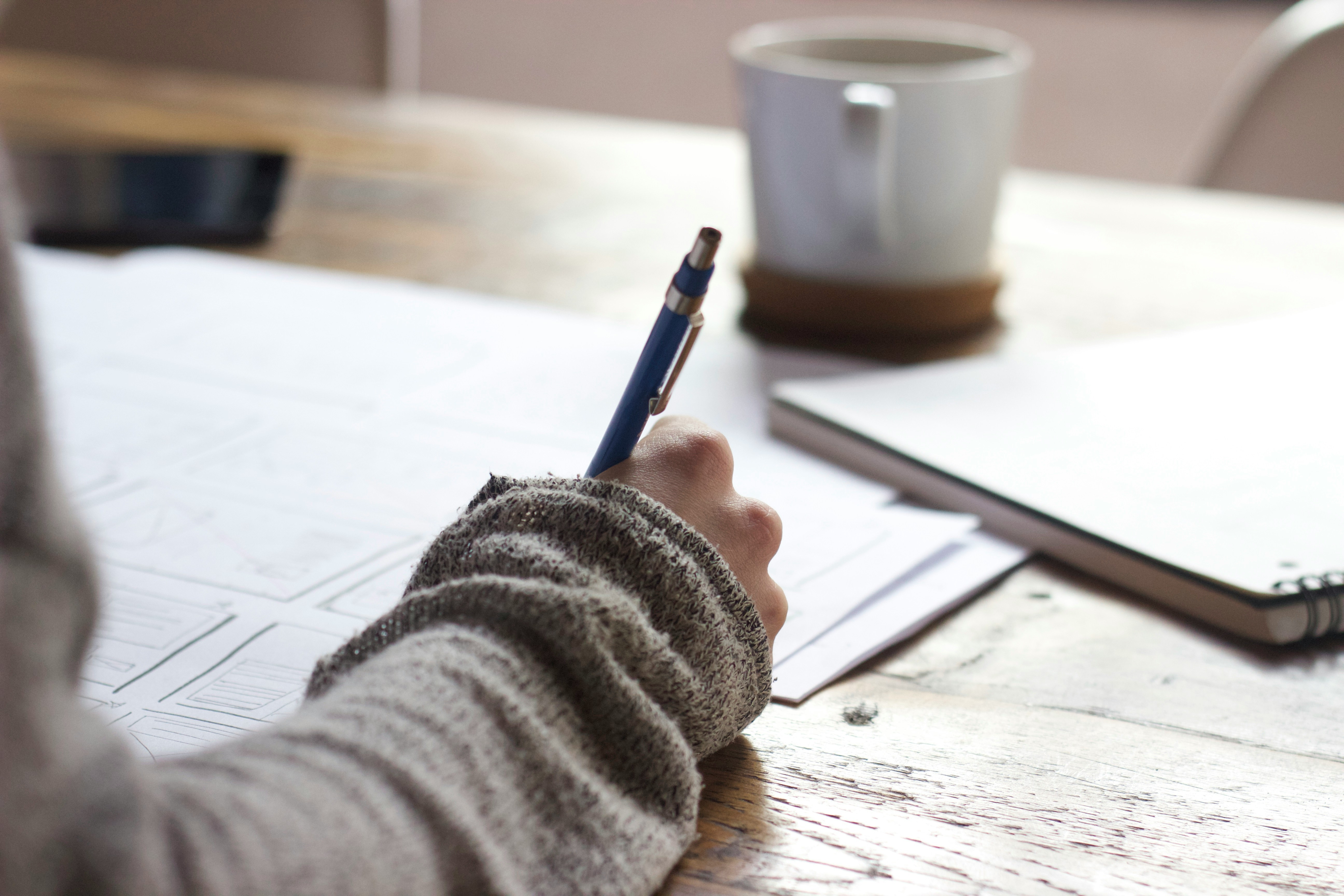 A woman's hand writing with pen on a notepad. Photo by Unseen Studio on Unsplash