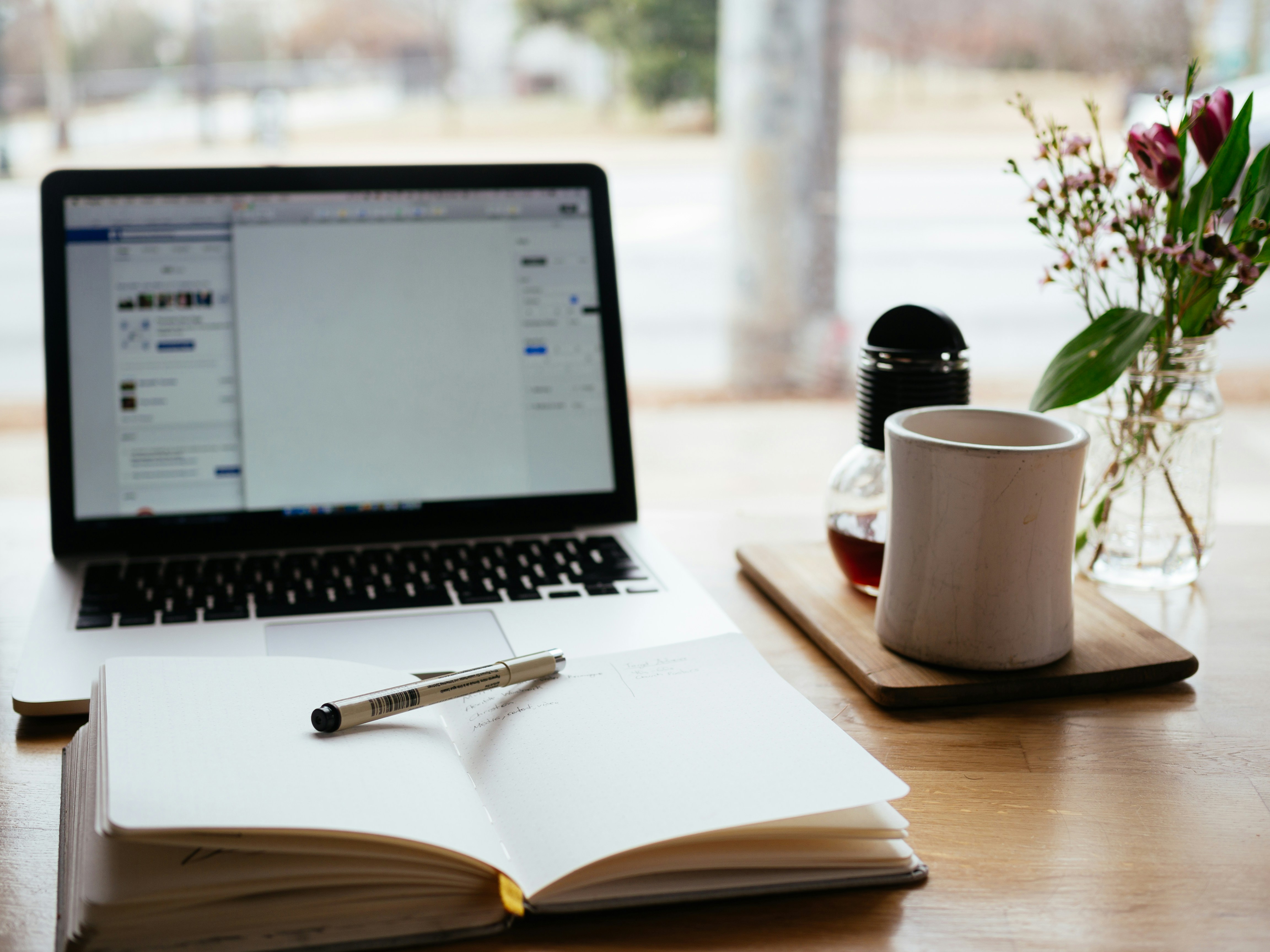 Table view of a laptop with social media open and a notepad