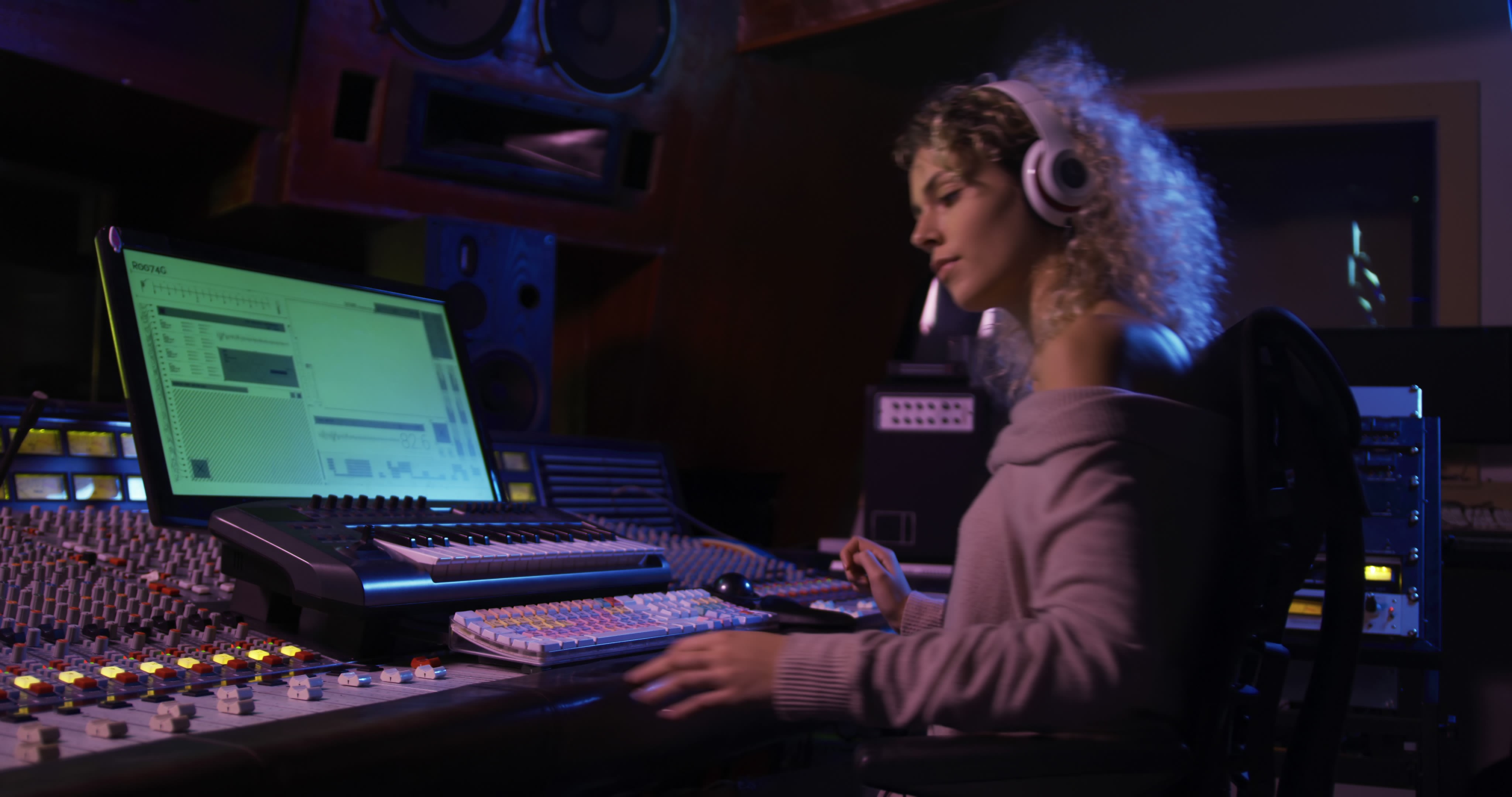 Female sound engineer immersing in music production at professional recording studio, adjusting audio on mixing desk. From pikwizard.com